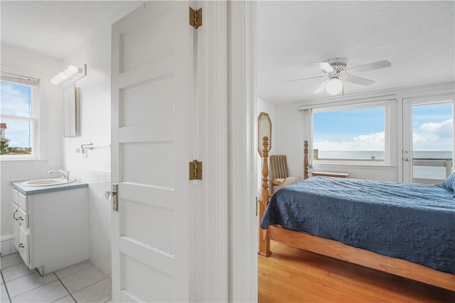 tiled bedroom with ceiling fan, sink, and a textured ceiling