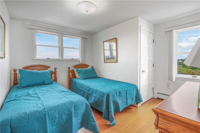 bedroom featuring light hardwood / wood-style floors and a baseboard heating unit