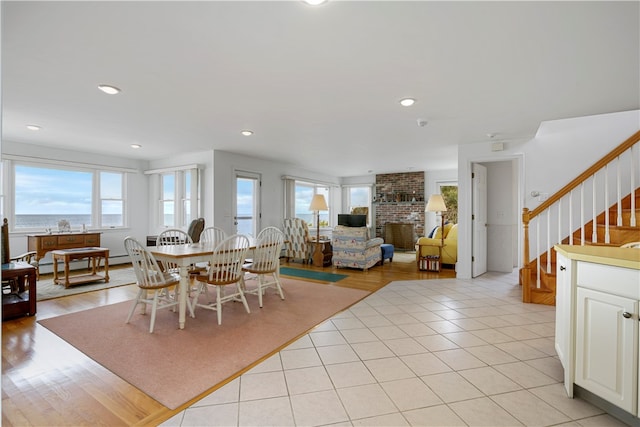 dining space featuring a fireplace, a baseboard heating unit, and light hardwood / wood-style flooring