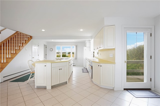 kitchen with a healthy amount of sunlight, white cabinets, light tile patterned flooring, and a baseboard radiator