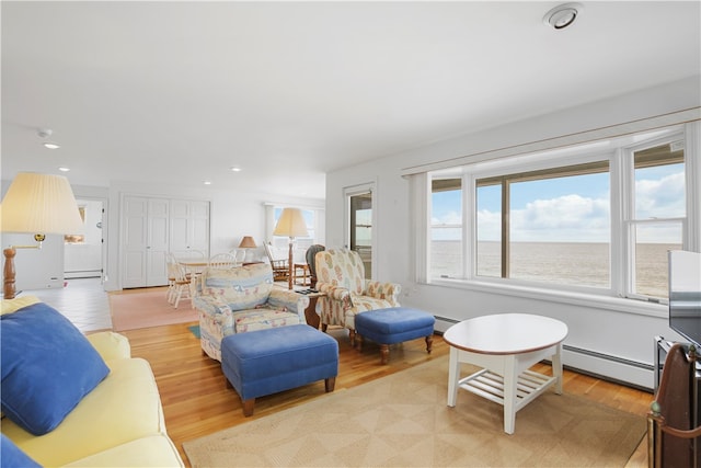 living room featuring a baseboard heating unit, light hardwood / wood-style floors, and a water view