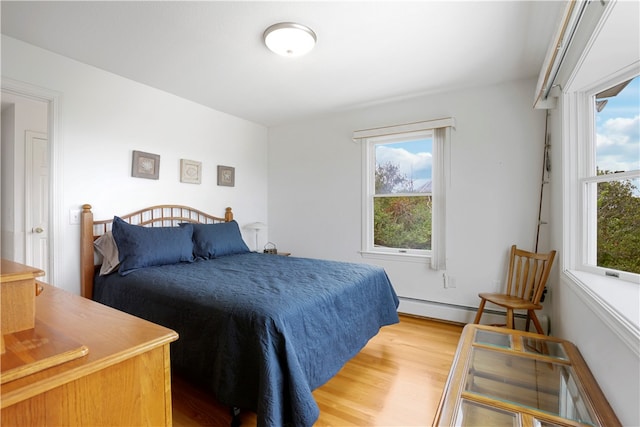 bedroom featuring multiple windows, baseboard heating, and light hardwood / wood-style flooring