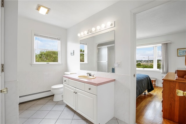 bathroom with vanity, baseboard heating, toilet, and a wealth of natural light