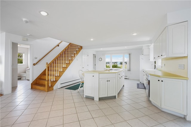 kitchen with light tile patterned flooring, a center island, a baseboard heating unit, and white cabinetry