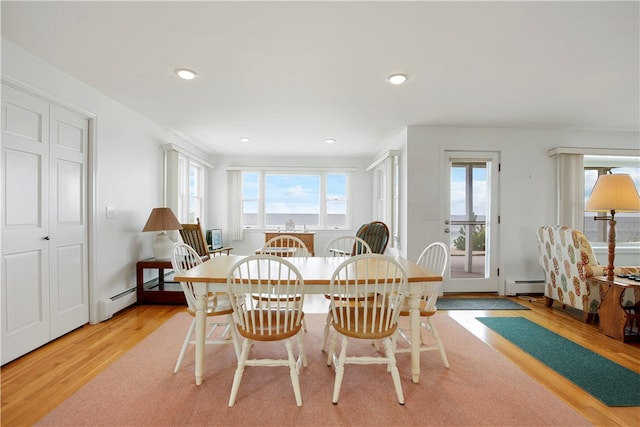 dining space featuring a baseboard heating unit and light wood-type flooring