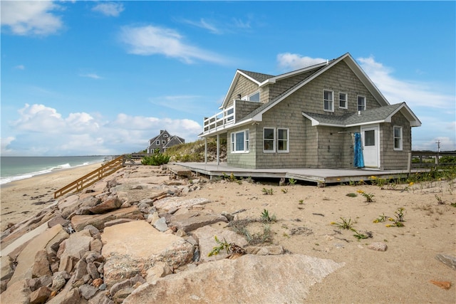 view of side of home featuring a deck with water view and a view of the beach