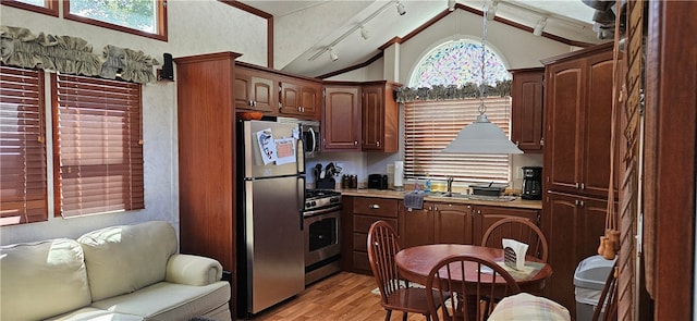 kitchen with appliances with stainless steel finishes, rail lighting, light wood-type flooring, and vaulted ceiling