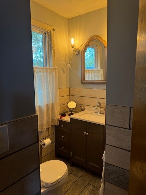 bathroom featuring tile walls, hardwood / wood-style floors, vanity, and toilet