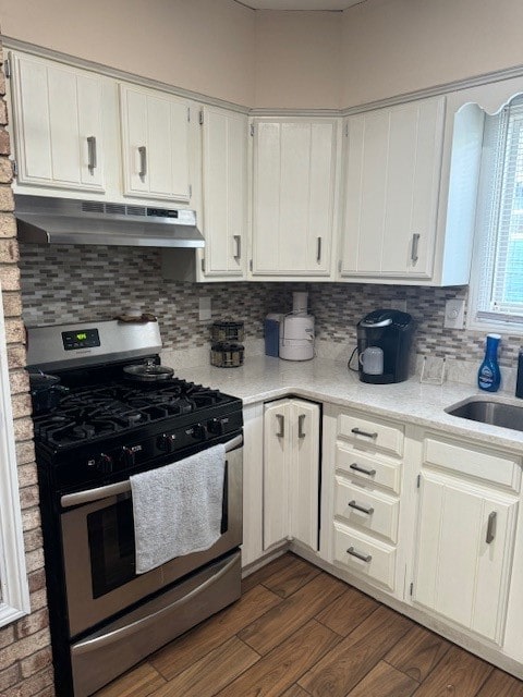 kitchen featuring sink, stainless steel gas stove, dark wood-type flooring, white cabinetry, and exhaust hood