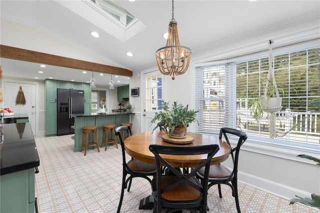 dining room featuring vaulted ceiling with skylight, ornamental molding, and an inviting chandelier