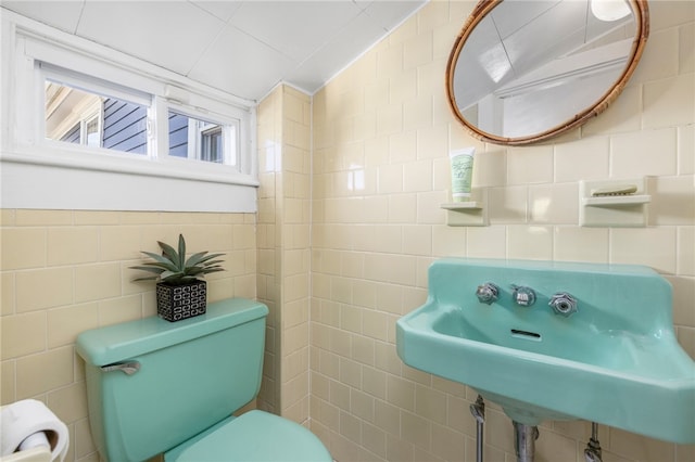 bathroom with tile walls, vaulted ceiling, toilet, and sink