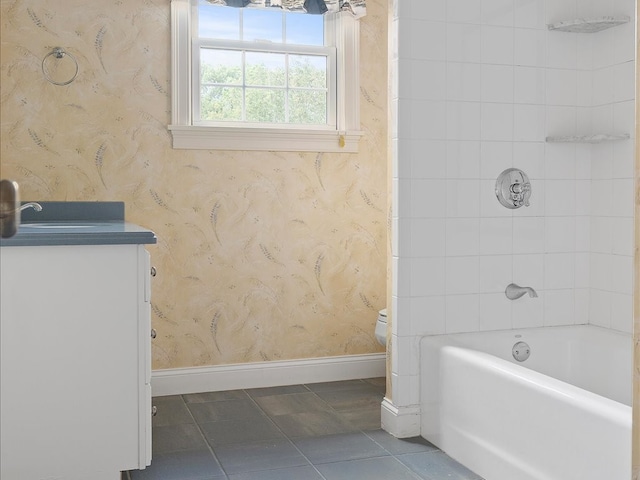 full bathroom with tiled shower / bath, vanity, and toilet