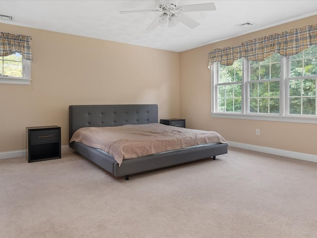 bedroom with multiple windows, light carpet, and ceiling fan