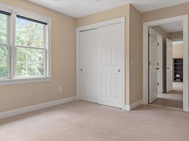 unfurnished bedroom featuring light colored carpet and a closet