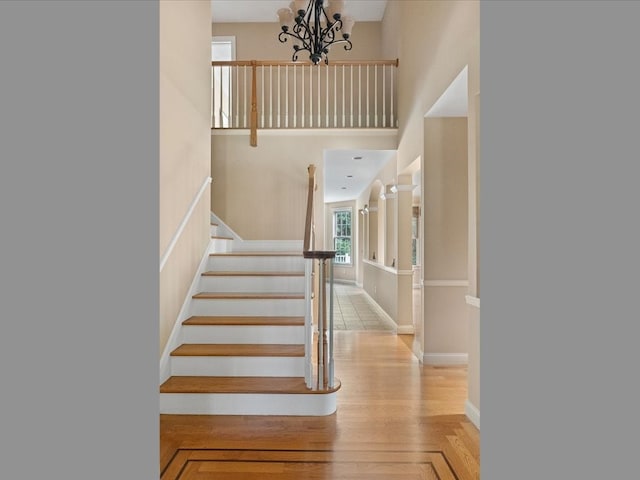 staircase with a notable chandelier and a towering ceiling