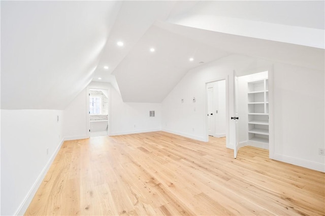 bonus room featuring built in shelves, light hardwood / wood-style floors, and lofted ceiling