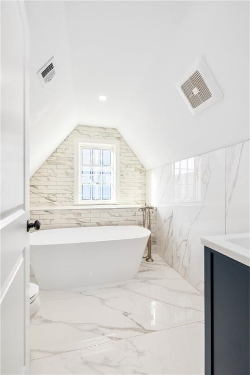 bathroom with vanity, a bath, lofted ceiling, and toilet