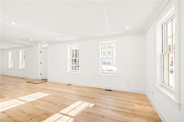 empty room with crown molding and light hardwood / wood-style floors