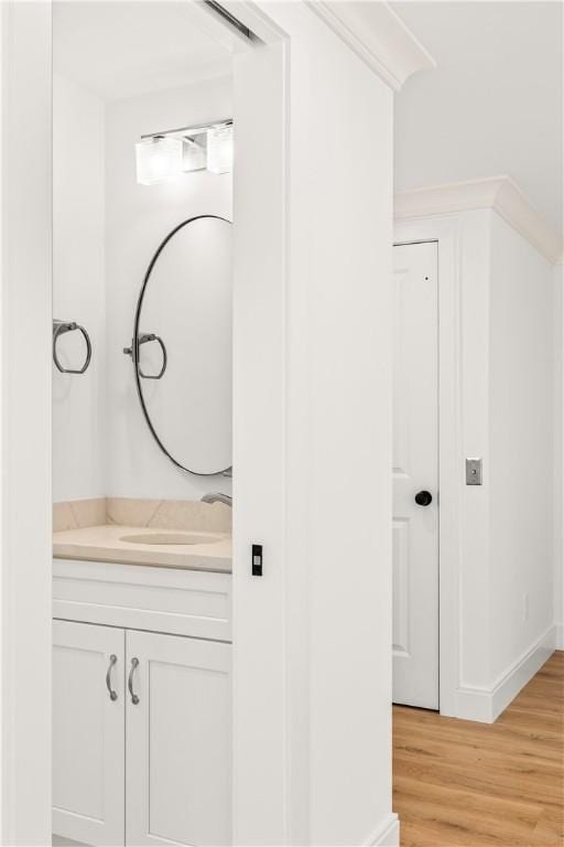 bathroom featuring vanity, hardwood / wood-style flooring, and crown molding