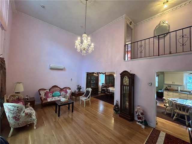 living room featuring light wood-type flooring, crown molding, a towering ceiling, and a chandelier