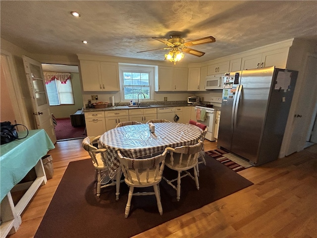 kitchen with light wood-type flooring, white appliances, white cabinetry, and ceiling fan