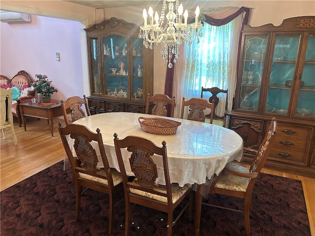 dining area with wood-type flooring, a notable chandelier, and a wall mounted air conditioner