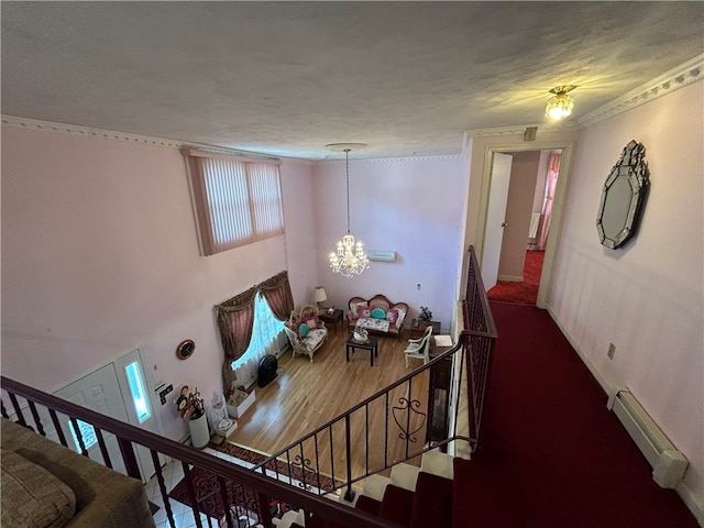 stairs with a textured ceiling, hardwood / wood-style flooring, baseboard heating, and a notable chandelier