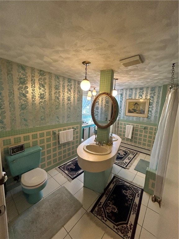 bathroom with a textured ceiling, tile patterned flooring, toilet, and a baseboard radiator