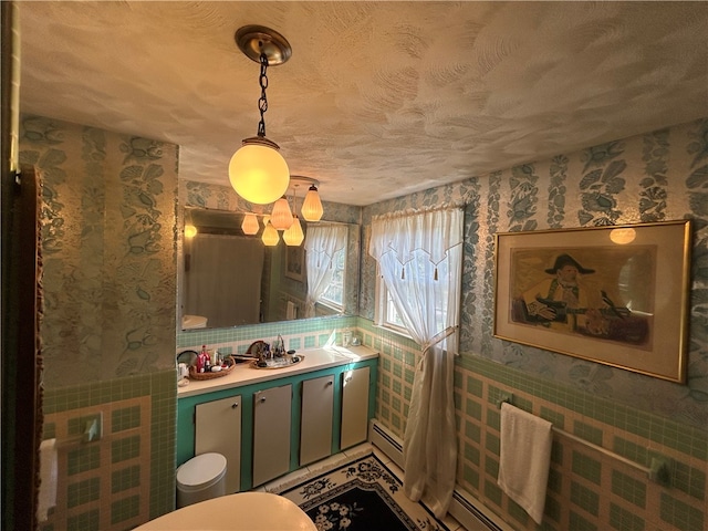 bathroom featuring a baseboard heating unit, vanity, toilet, and a textured ceiling