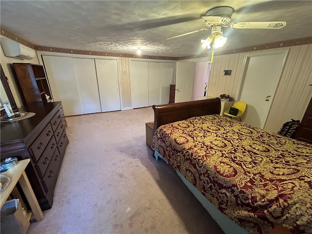 bedroom featuring multiple closets, ceiling fan, light colored carpet, and a textured ceiling