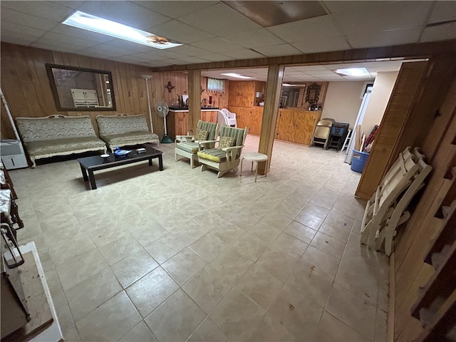 tiled living room featuring wooden walls and a paneled ceiling