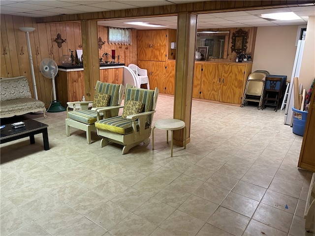 interior space with a drop ceiling and wood walls