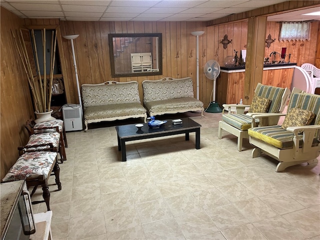 living room featuring a paneled ceiling and wood walls