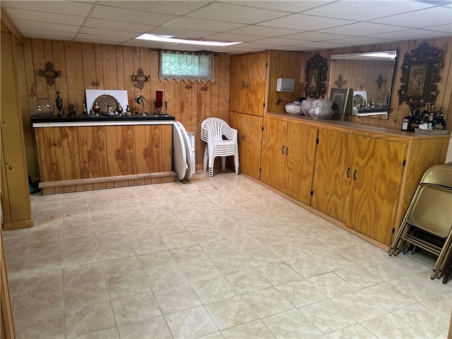 interior space featuring bar area, a drop ceiling, and wooden walls