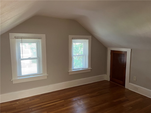 additional living space with vaulted ceiling, plenty of natural light, and dark hardwood / wood-style flooring