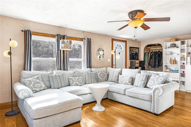 living room with ceiling fan, a textured ceiling, and hardwood / wood-style floors