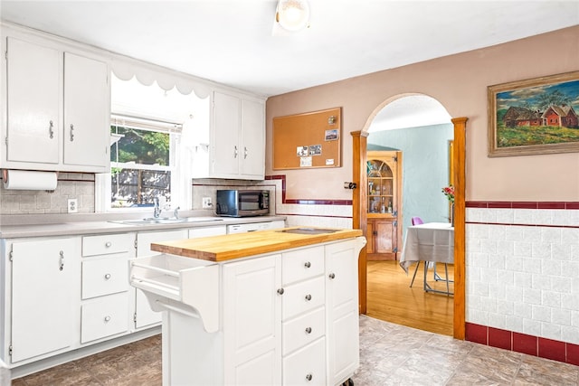 kitchen with stainless steel appliances, sink, tile walls, and white cabinetry