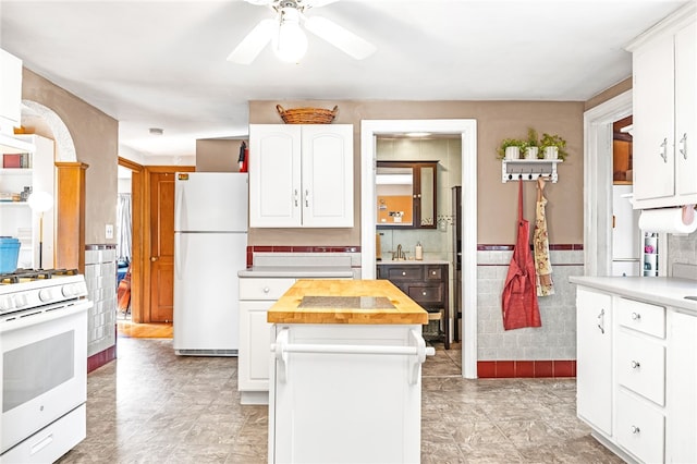 kitchen featuring tile walls, white cabinetry, a kitchen island, white appliances, and butcher block countertops