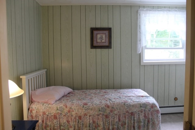 carpeted bedroom featuring wooden walls and baseboard heating