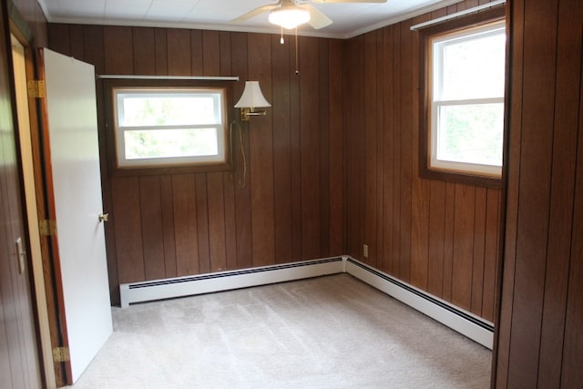 empty room featuring ceiling fan, light colored carpet, wooden walls, and plenty of natural light