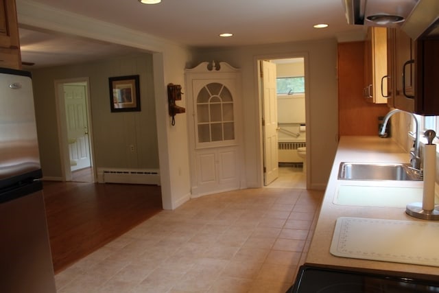 kitchen with sink, radiator heating unit, light hardwood / wood-style flooring, a baseboard heating unit, and stainless steel refrigerator