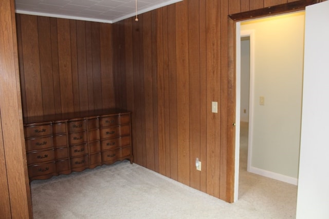 unfurnished room featuring wooden walls and light colored carpet