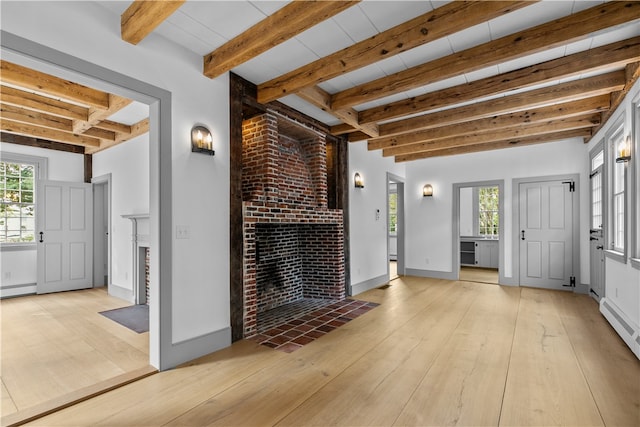 interior space with light hardwood / wood-style floors, beam ceiling, a baseboard heating unit, and a brick fireplace