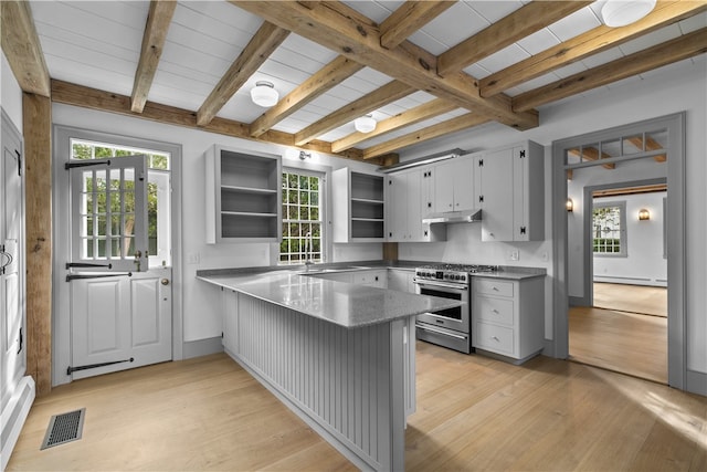 kitchen featuring a healthy amount of sunlight, high end stove, kitchen peninsula, and beamed ceiling