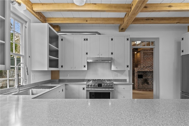 kitchen with beam ceiling, sink, stainless steel stove, and white cabinets