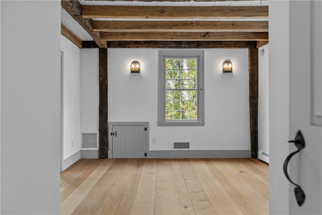 empty room with a baseboard heating unit, radiator, beam ceiling, and light hardwood / wood-style floors