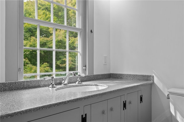 bathroom featuring a wealth of natural light, vanity, and toilet