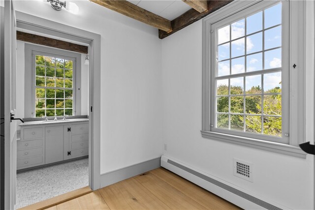 interior space featuring light hardwood / wood-style flooring, a wealth of natural light, beam ceiling, and baseboard heating