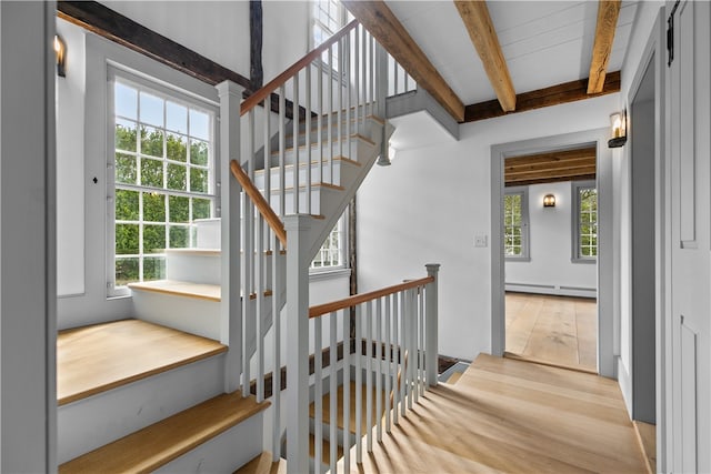 stairs featuring hardwood / wood-style flooring, a baseboard radiator, and plenty of natural light