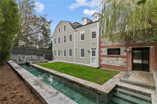 rear view of house with a fenced in pool, a yard, and a patio